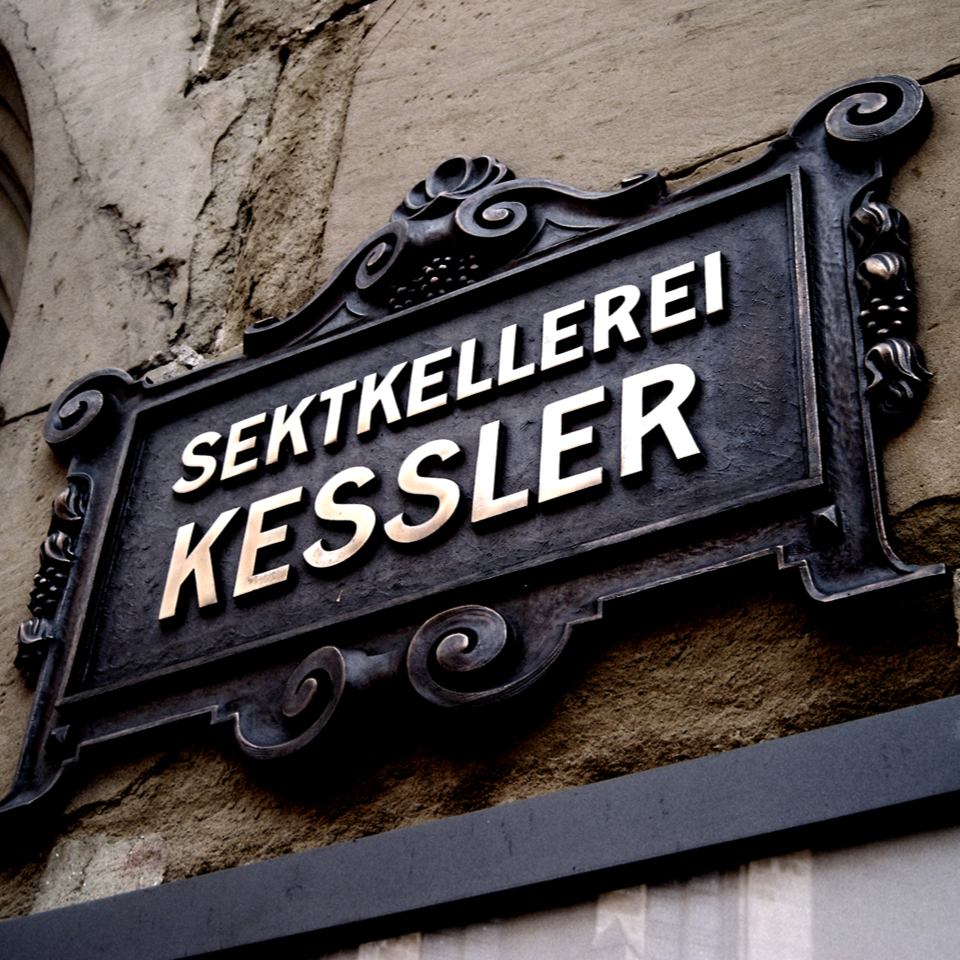 Schild mit der Aufschrift „Sektkellerei Kessler“ an einer Gebäudefassade