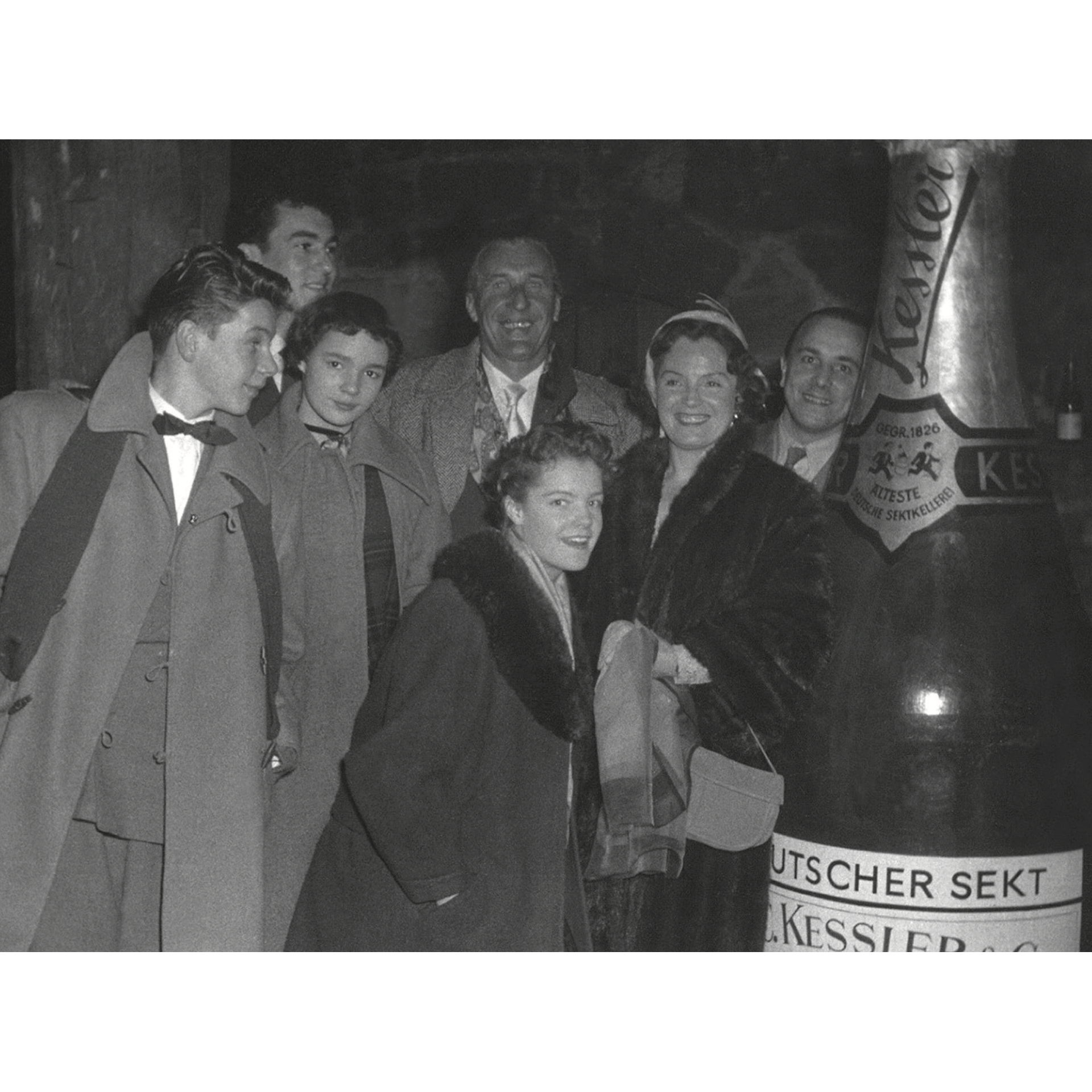 Historische Aufnahme einer Gruppe von Personen neben einer großen Kessler Sektflasche