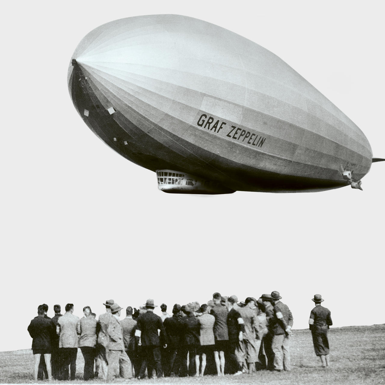 Historische Aufnahme eines Zeppelins „Graf Zeppelin“ über einer Menschenmenge